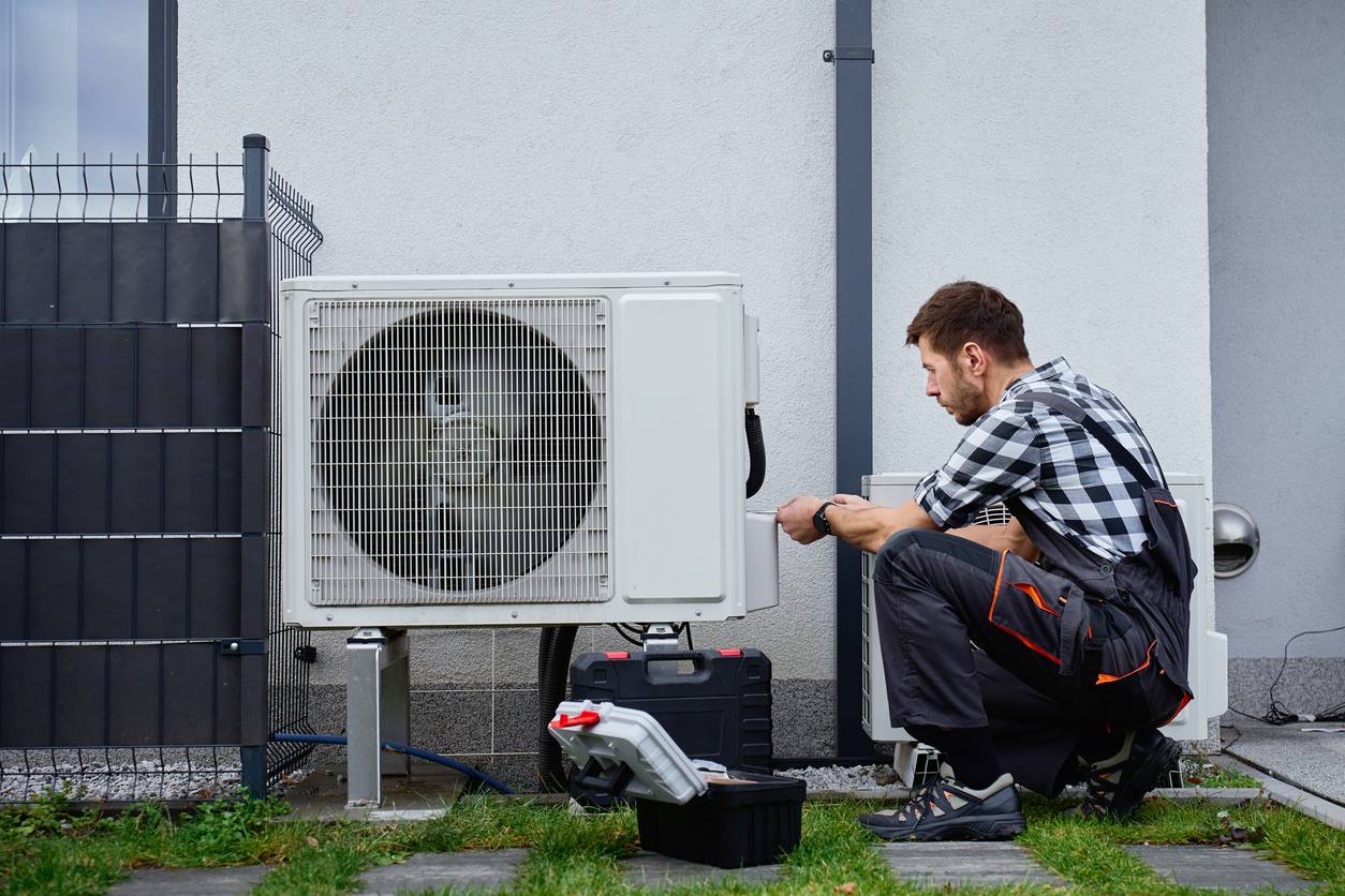 Technician installing a ductless mini-split outdoor unit at a Long Island home